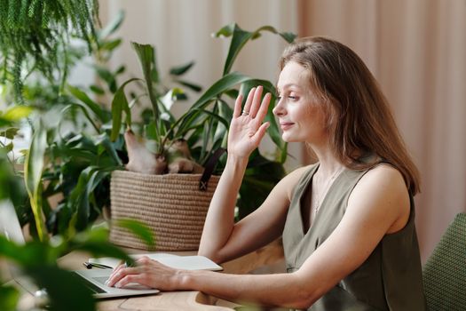 一名中年妇女在植物环绕的家庭办公室里参加视频通话