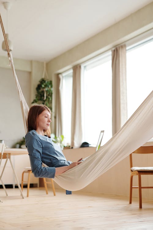 A Woman Working while Lying on a Hammock