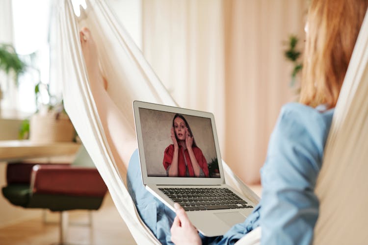 A Person Lying On The Hammock While Using Laptop