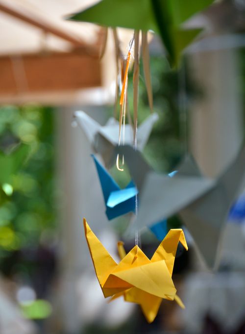 Free Colorful handmade orizuru birds hanging on ropes on blurred green plant in summer day Stock Photo