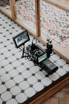 High-quality video camera on hexagonal tiled floor with a colorful rug nearby.
