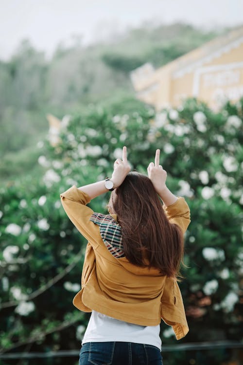 Woman showing fuck gesture near bushes of green plants