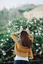 Woman showing fuck gesture near bushes of green plants