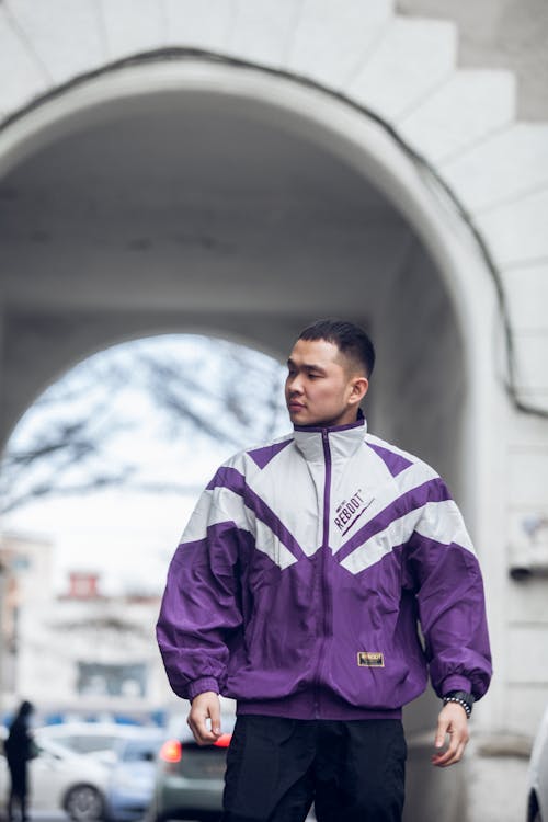 Asian man standing near arch on city street