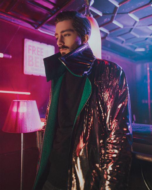 From below of serious stylish bearded male in trendy outerwear standing near counter in modern restaurant