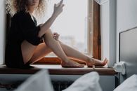 Woman in Black Dress Sitting on Window