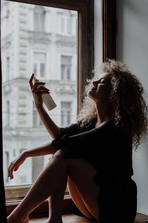 Free Woman in Black Shirt Sitting on Window Stock Photo