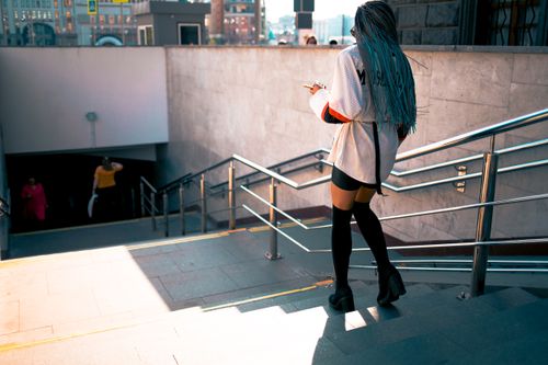 Free Stylish woman with braided hair walking down urban subway stairs in daylight. Stock Photo