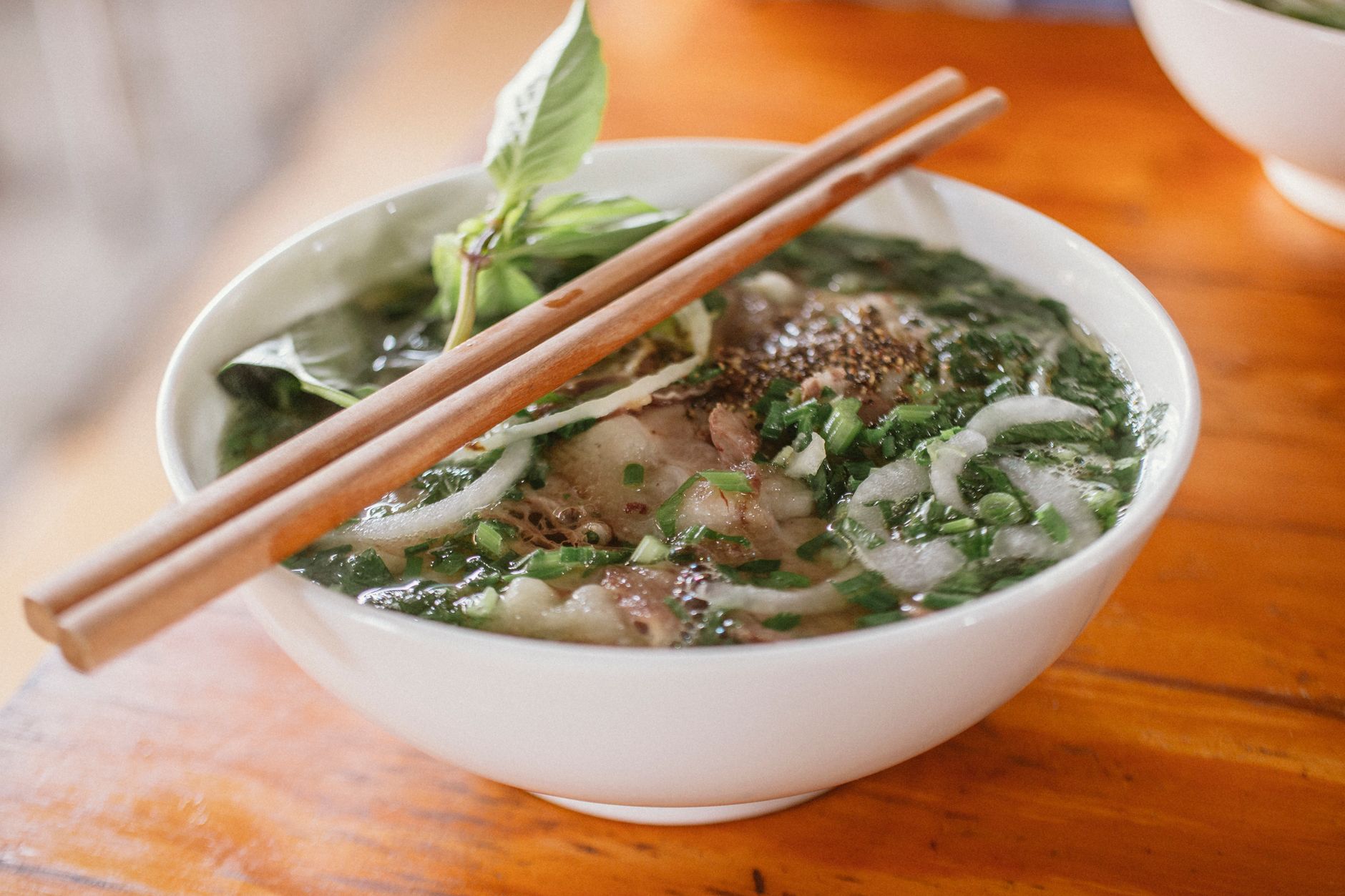 A steaming bowl of Vietnamese Pho served on a street vendor's table