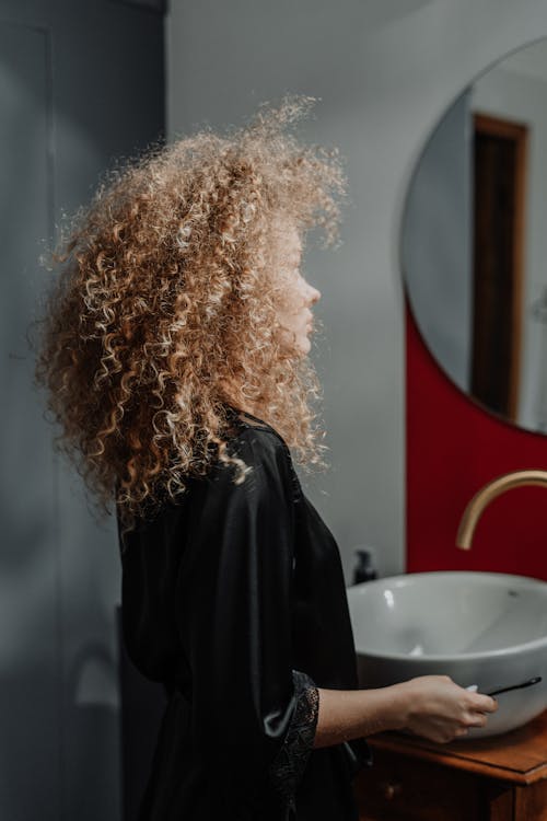 Woman in Black Jacket Standing Near Round Mirror