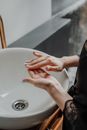 Person in Black Long Sleeve Shirt Holding White Ceramic Sink