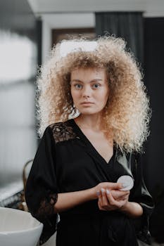 A young woman with curly hair engages in her morning beauty routine indoors.