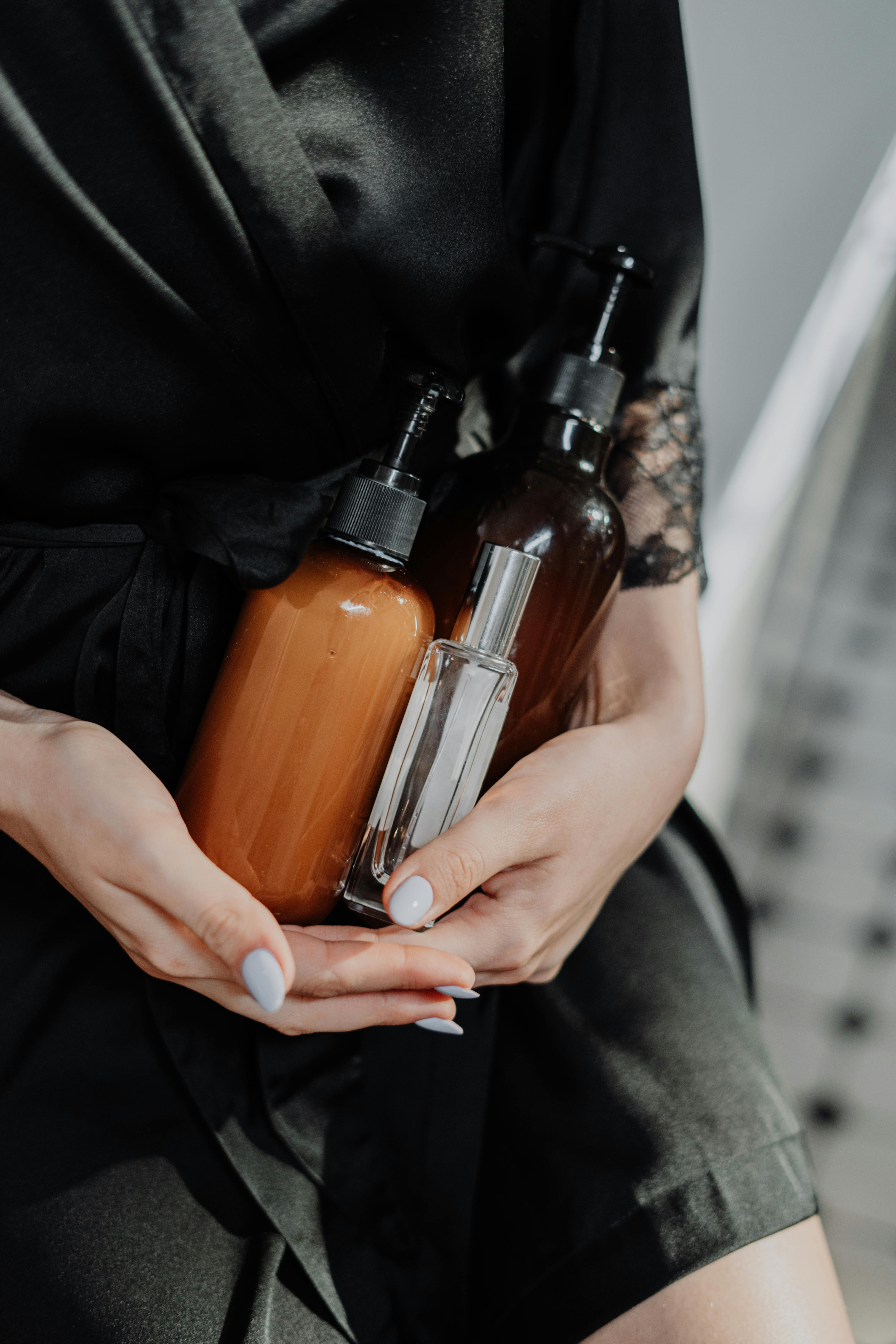 A woman in a black silk robe holds eco-friendly cosmetic bottles, highlighting zero waste lifestyle.