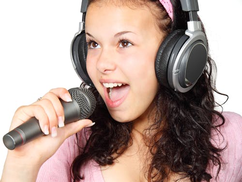 Free A Girl Holding a Microphone With a Headphone Stock Photo