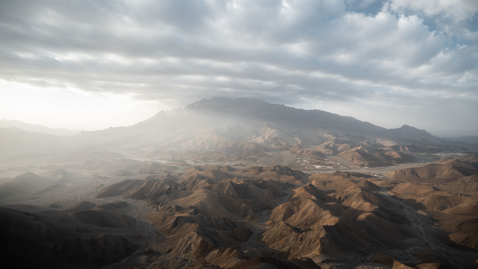Stunning aerial landscape of mountains in Ad Dhahirah Governorate, Oman under a cloudy sky.