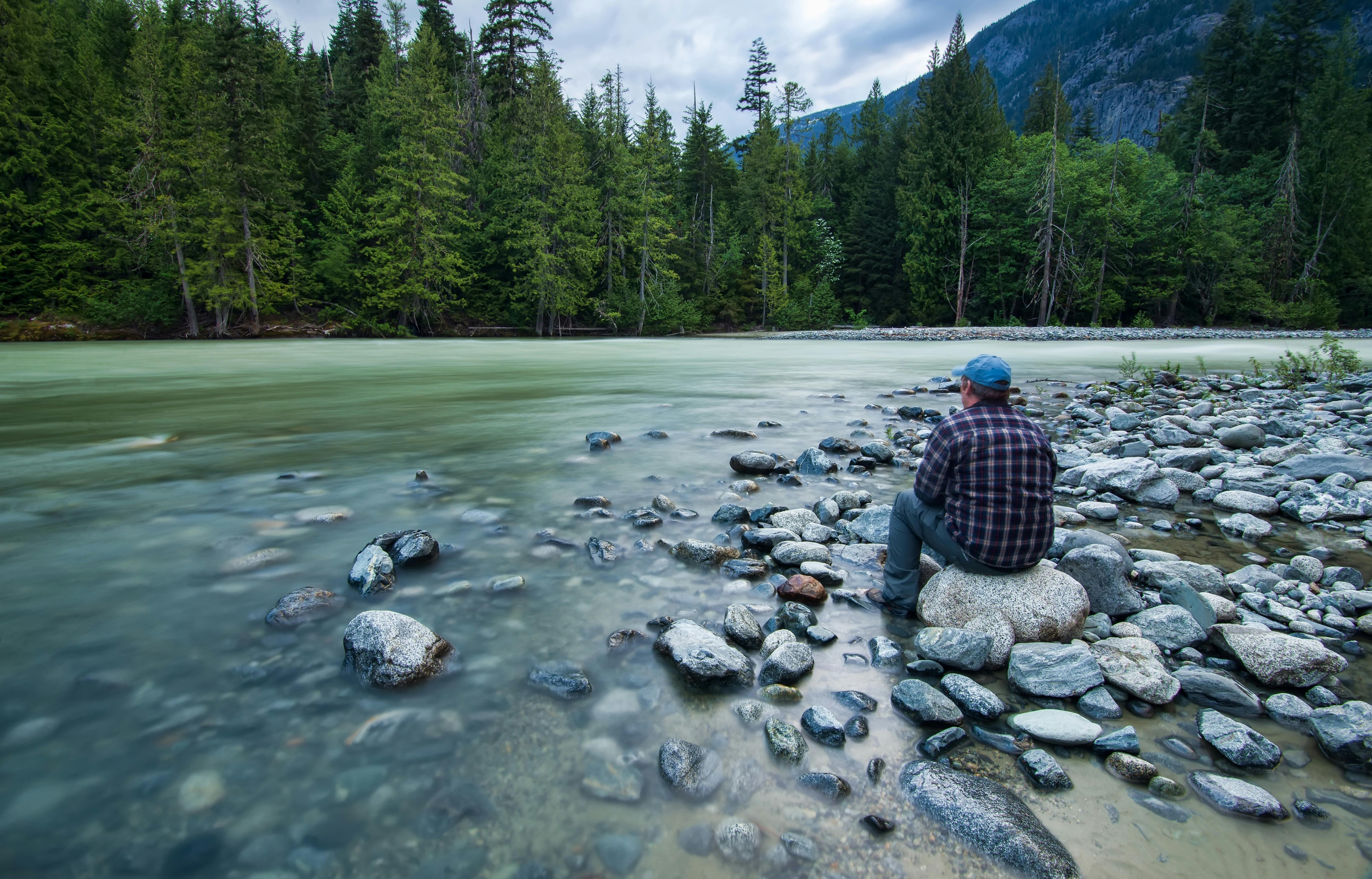 person sitting on stone near body of water