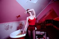 一位时尚女子在装饰独特的阁楼浴室里身着红色服装摆姿势