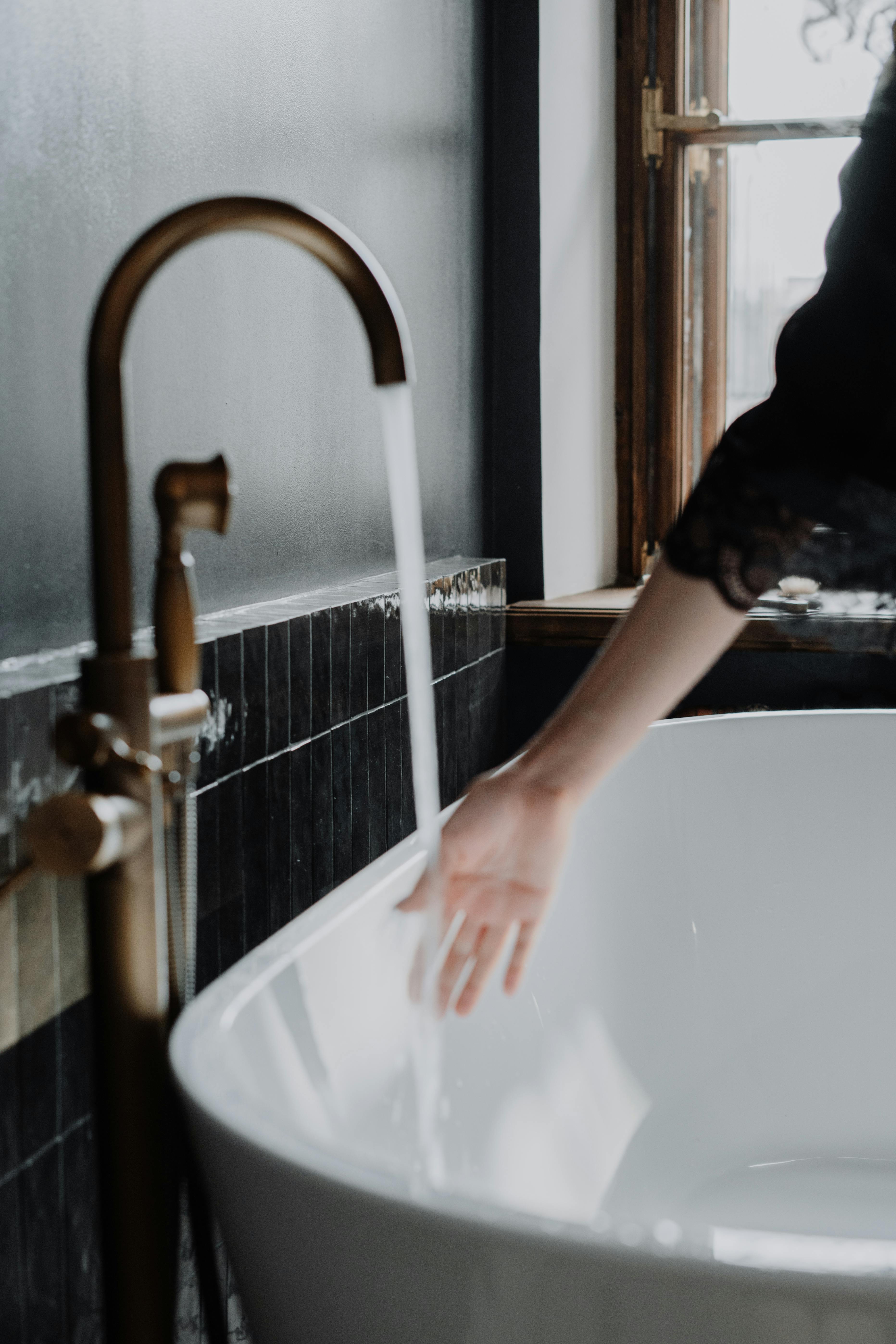 Person in Black T-shirt Washing Hand on Bathtub · Free Stock Photo