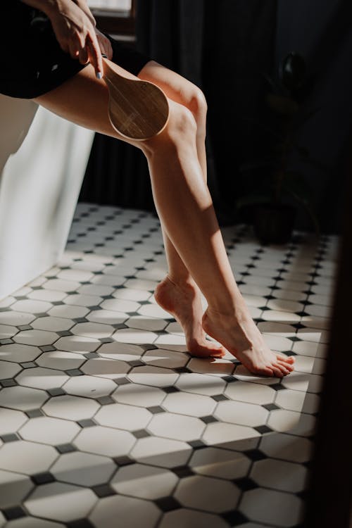 Person in White Pants Standing on White and Black Floor Tiles