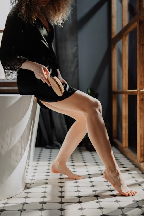 Crop woman in silk robe in bathroom