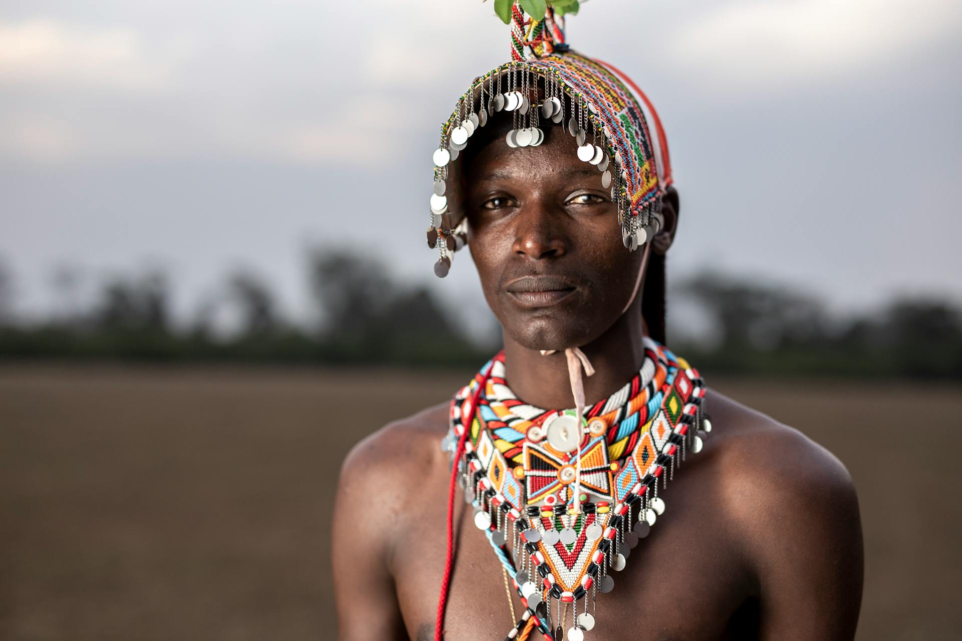 A Maasai warrior showcasing traditional beadwork and cultural attire in the Kenyan landscape.