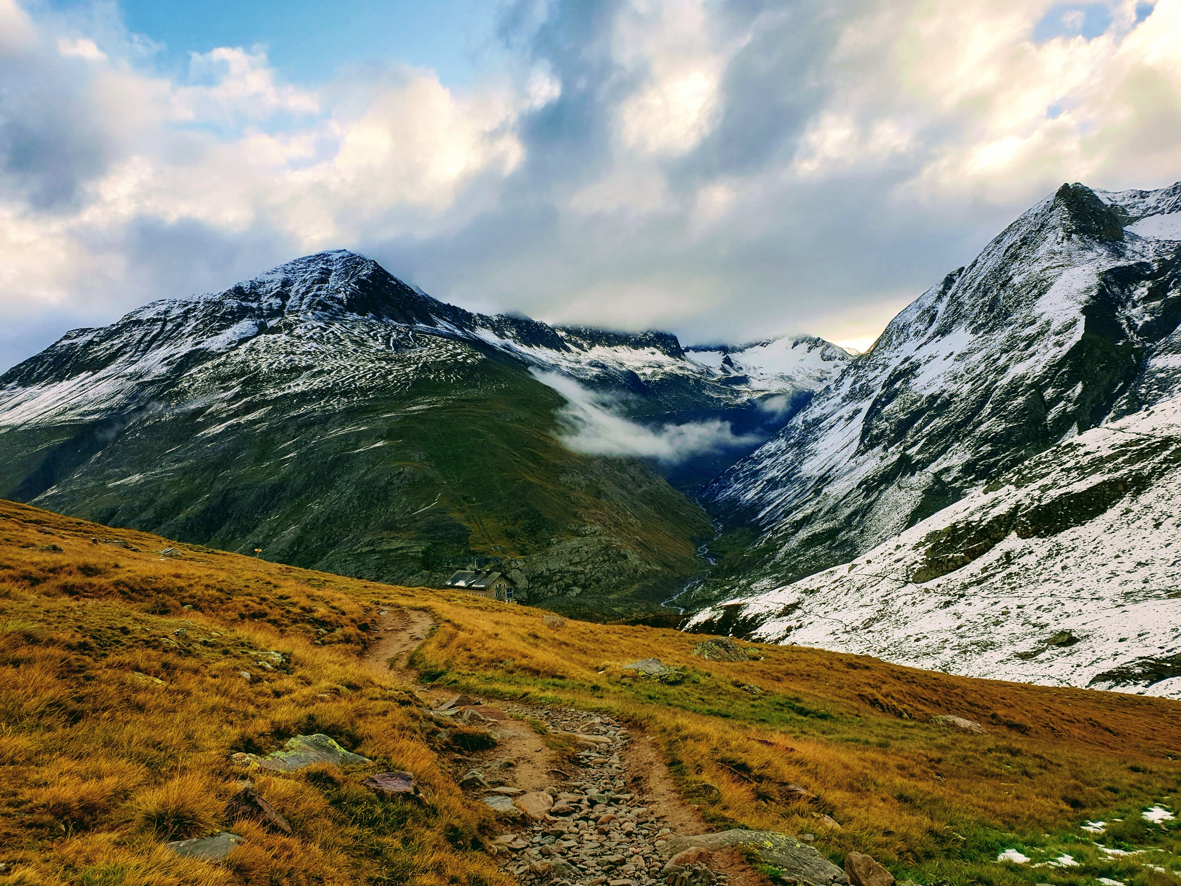 Magnificent scenery of rough majestic mountains peaks covered with dry vegetation and snow under cloudy sky