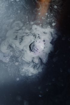 彩色沐浴炸弹的特写镜头在水中溶解，形成漩涡图案