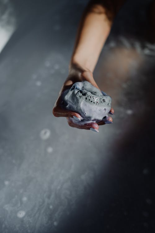 Person Holding Ice on Brown Plastic Container