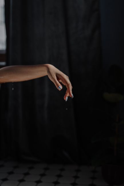 A graceful hand dripping water, captured in a dark, serene setting, highlighting relaxation.
