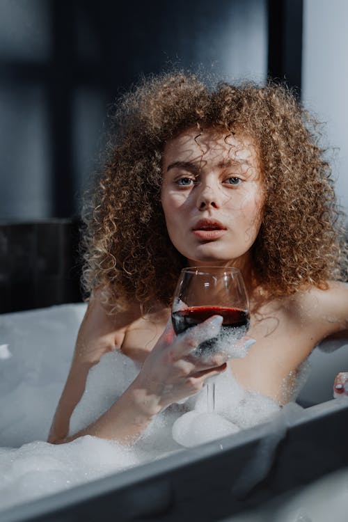 Free Woman in White Bath Tub Holding Clear Drinking Glass Stock Photo