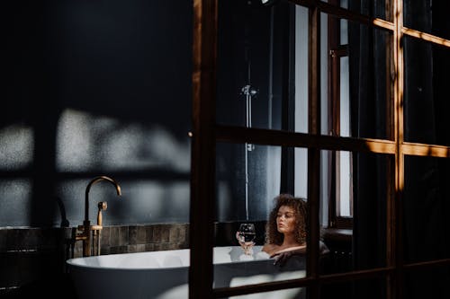 Woman in Bathtub Near Window