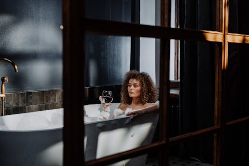 Free Woman in White Tank Top Sitting on White Bed Stock Photo