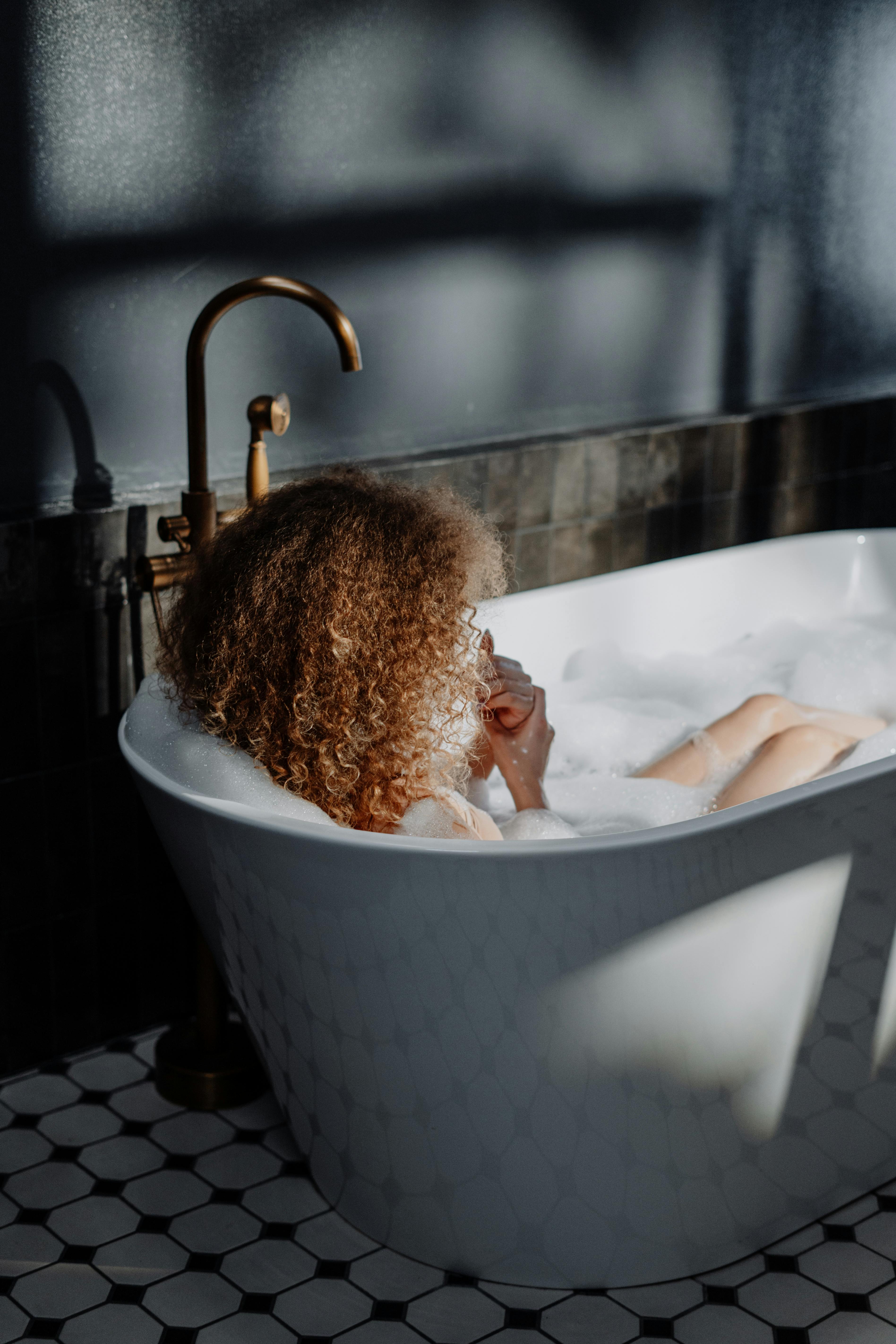 woman in bathtub with brown curly hair