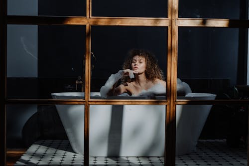 Woman in Black Long Sleeve Shirt Sitting on White Bathtub