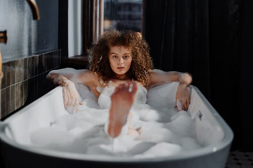 Curly-haired girl in bubble bath