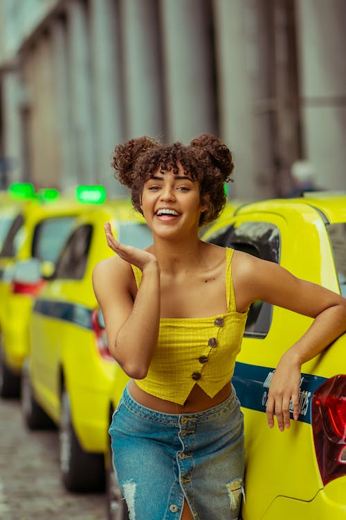 Free Cheerful ethnic woman standing gracefully near taxi cars Stock Photo