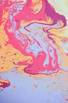 Abstract vibrant background of multicolored paints including pink beige and blue colors swirling on smooth surface