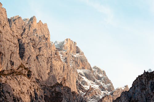 Breathtaking landscape of rocky mountains with white snowy peaks in highland under bright sky