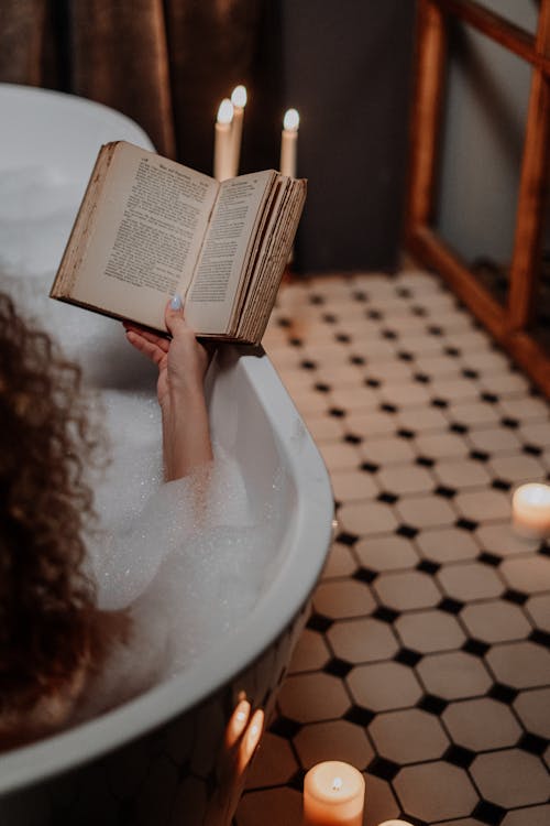 Free Person Reading Book in Bathtub Stock Photo