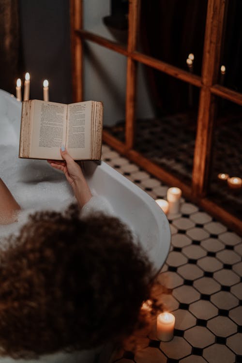 Person Reading Book on Bathtub