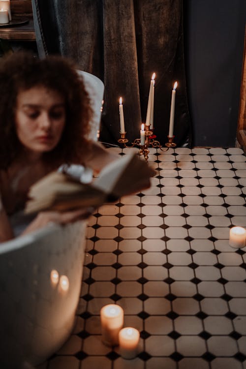 Woman Holding Lighted Candle in Front of Lighted Candles