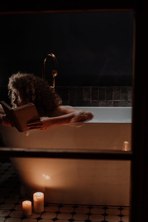 Free Woman in Bathtub Holding Book Stock Photo