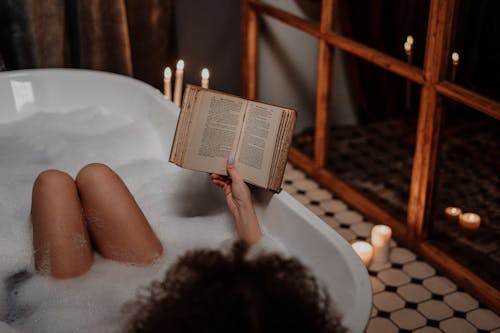 Free Person Reading Book on Bathtub Stock Photo