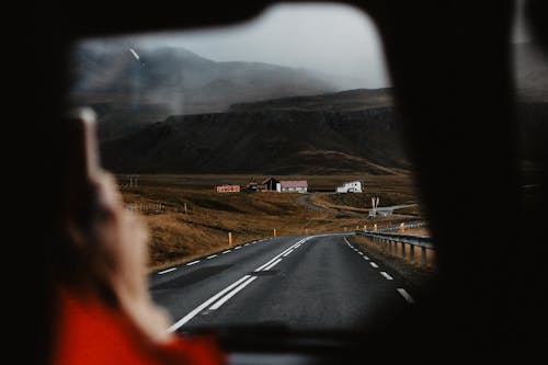 Free A scenic drive through a winding road in a rural mountain landscape, viewed from a vehicle. Stock Photo