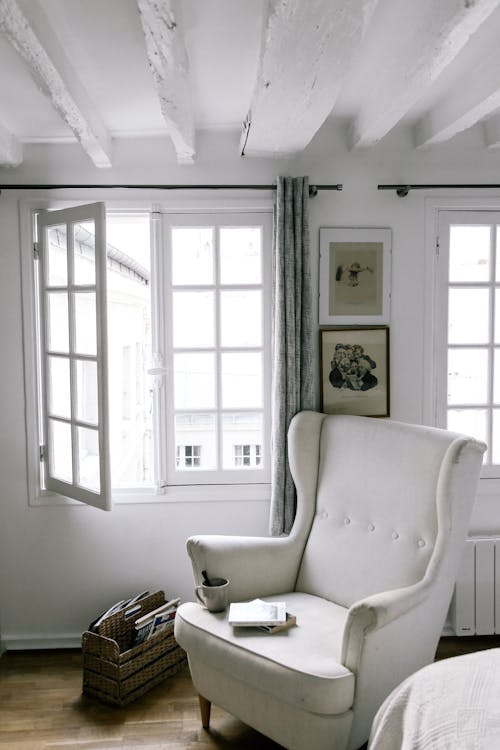 Free A White Armchair Near a White Wooden Framed Window Stock Photo