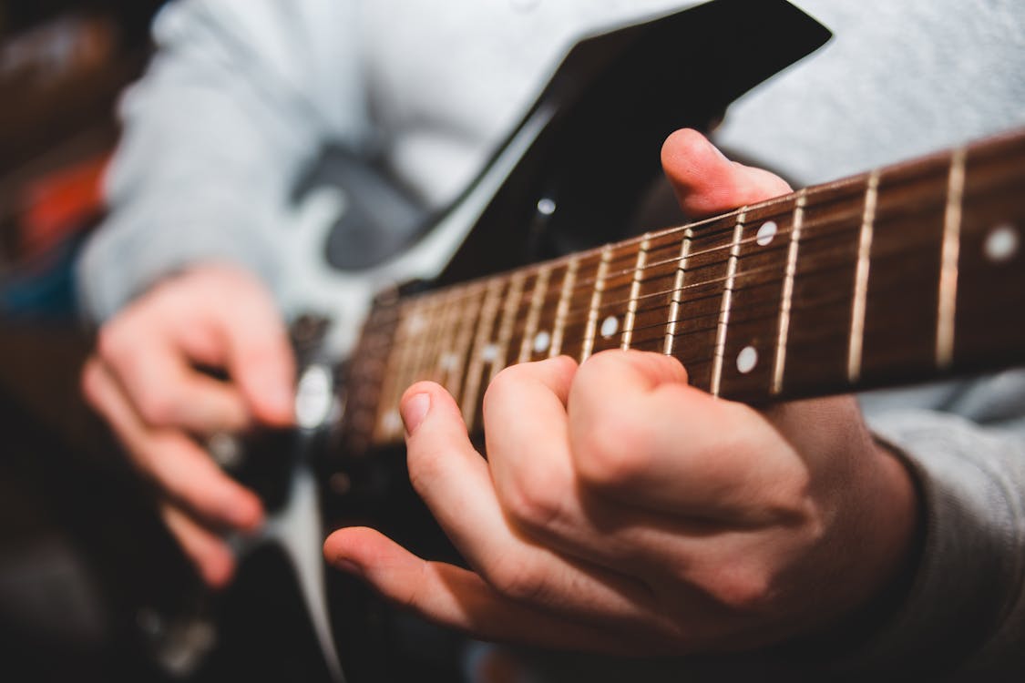 Free Selective focus of crop unrecognizable male musician playing electric guitar during music lesson Stock Photo