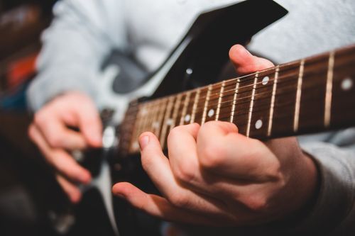Free Selective focus of crop unrecognizable male musician playing electric guitar during music lesson Stock Photo