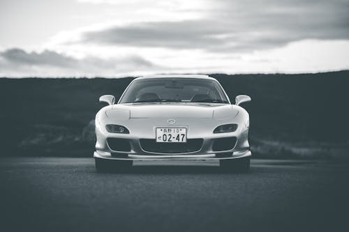 Free Black and white luxury car on asphalt roadway against field and cloudy sky Stock Photo