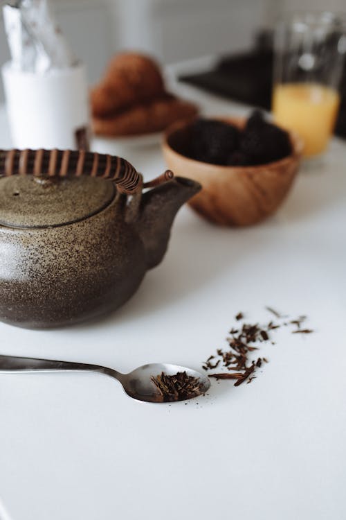 Close-Up Shot of a Brown Ceramic Teapot beside a Spoon