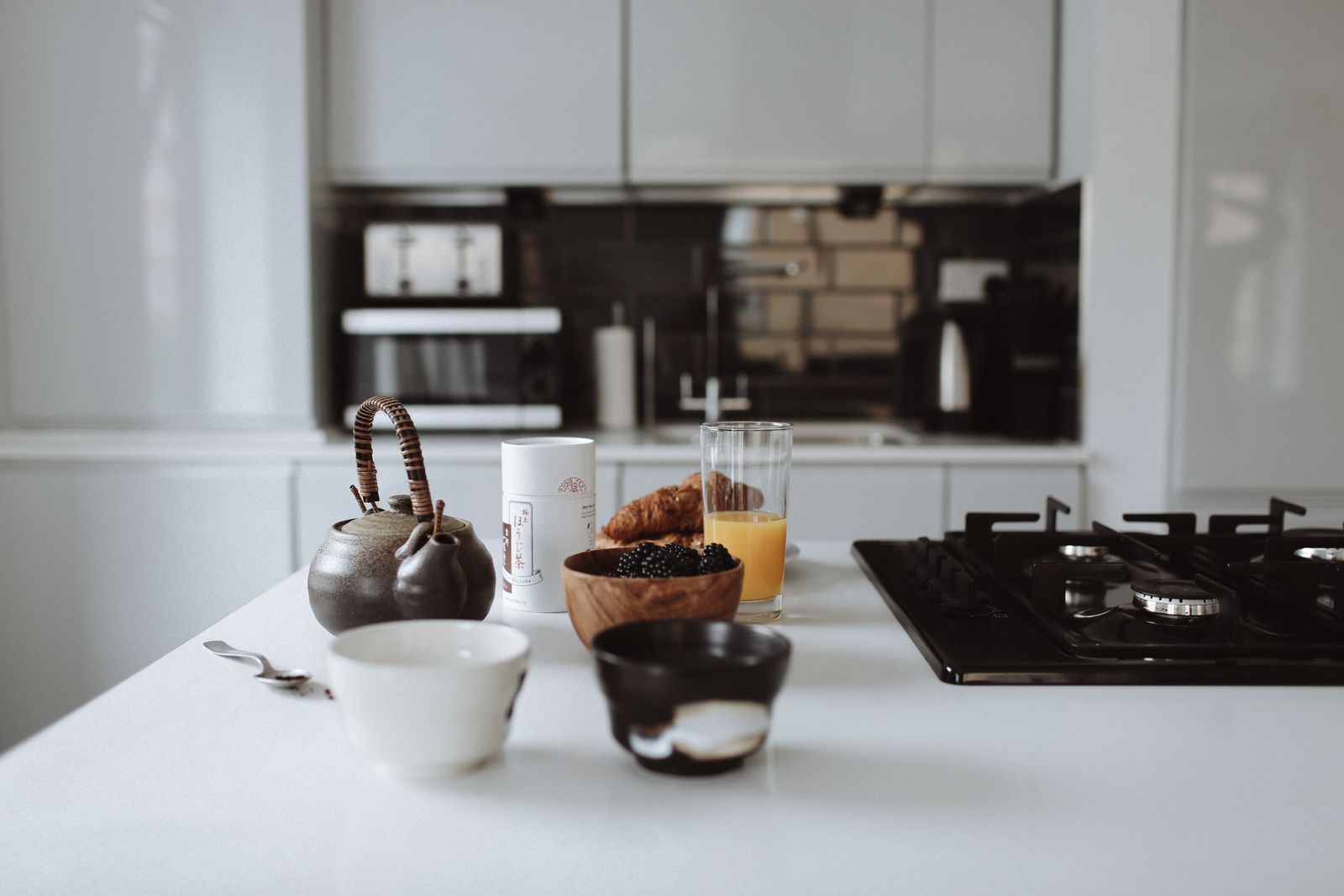 A stylish breakfast setup in a modern kitchen featuring croissants, orange juice, and berries on a counter.